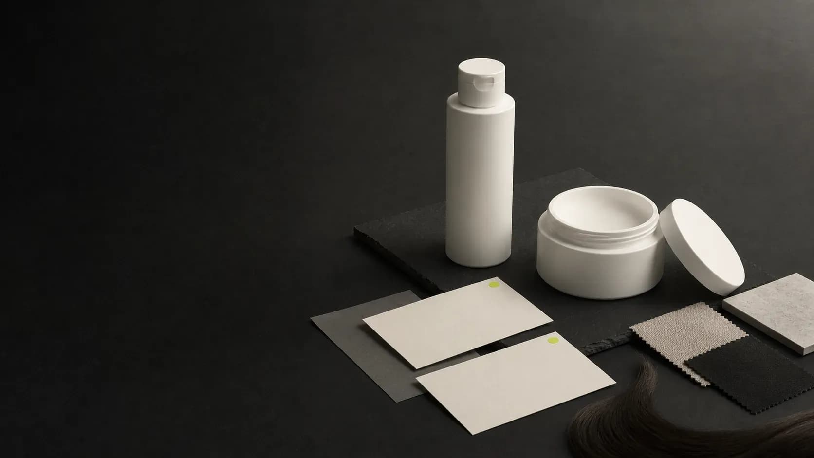 An unbranded Conditioner bottle and Hair Mask jar beside blank decision cards, material swatches, and a hair sample on a dark planning surface.